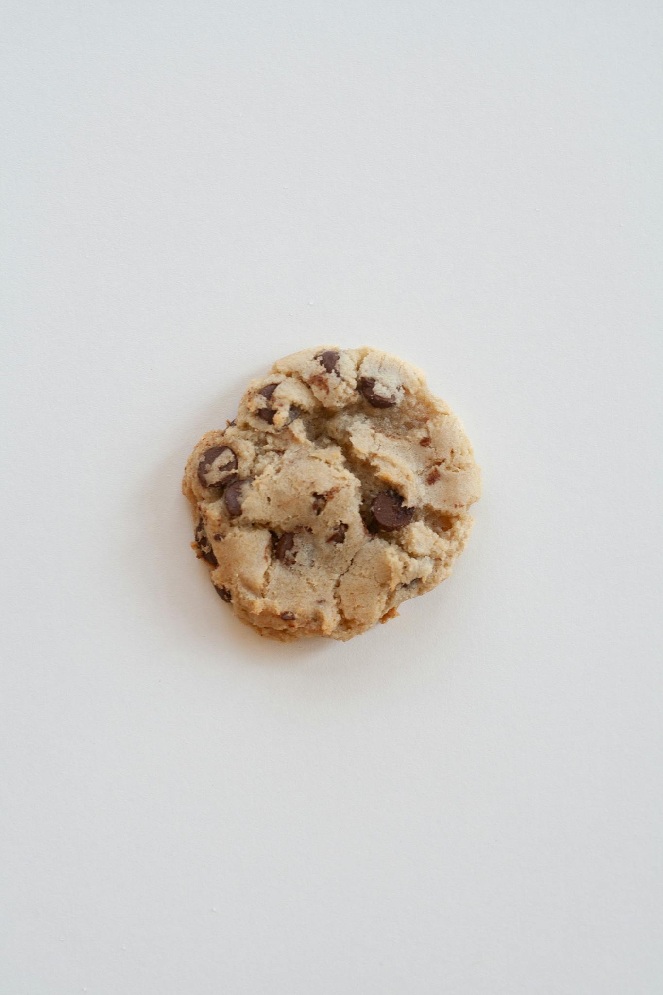 A single homemade chocolate chip cookie shot on a clean, minimalist background.