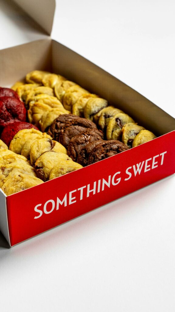 A variety of fresh cookies in a red box with 'Something Sweet' text.